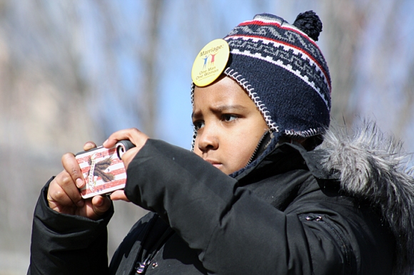 Nine-year-old Denzel Brown of Aurora snaps a photo during one of the speeches. Brown wore one of the yellow buttons supporting "Marriage: One Man One Woman."