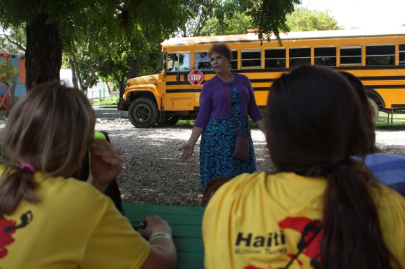 New Life's guest house coordinator, Lisa, shares the rules with the team. (The bus behind her was our transportation from the airport to the children's home.)